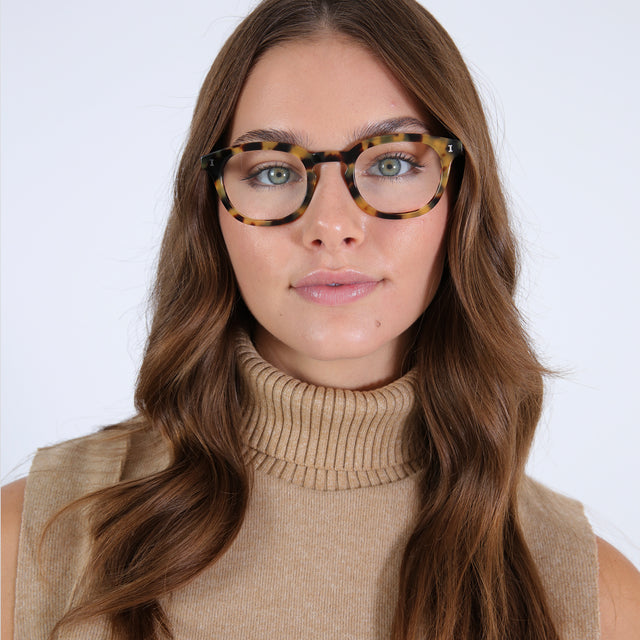 Brunette model with curled hair wearing Slope Optical Tortoise Optical