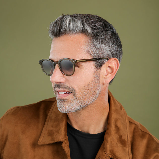 Another angle of man in a brown suede jacket looking right wearing Slope Sunglasses Olive with Grey Gradient