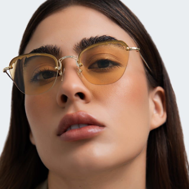 Close up of woman in a beige blouse wearing Sorrento Sunglasses Gold with Honey Flat See Through