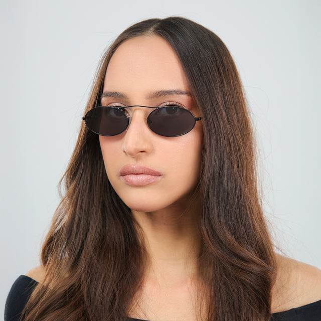 Woman with brown hair in an off-the-shoulder blouse wearing Sydney Sunglasses Matte Black with Grey