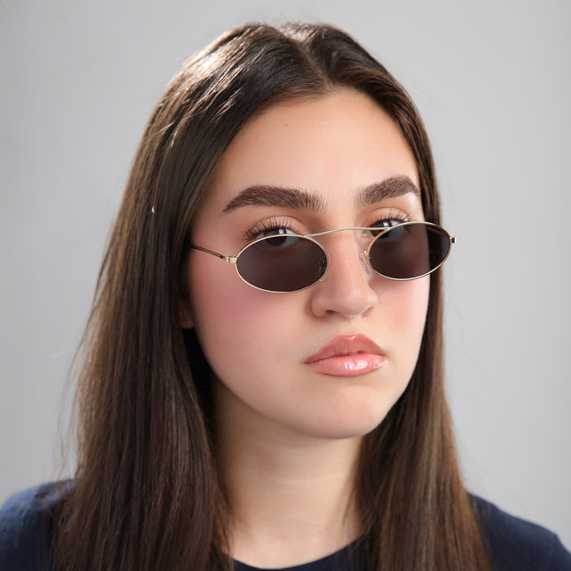 Brunette model in front of a grey wall wearing Sydney Sunglasses Gold with Grey