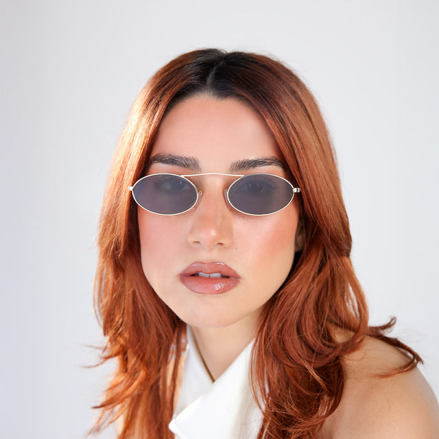 Woman with red hair in a white blouse wearing Sydney Sunglasses Gold with Grey