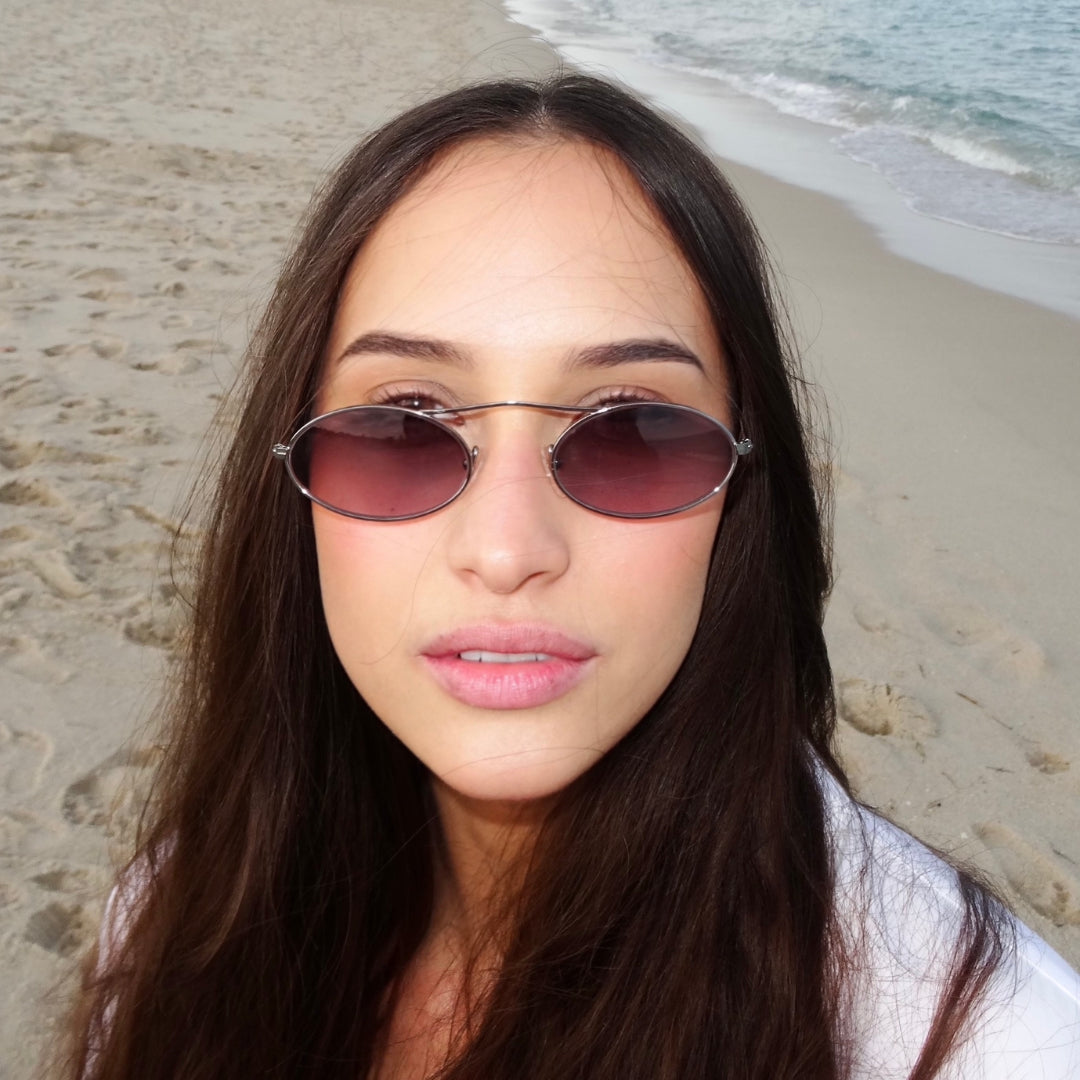 Woman wearing Sydney Sunglasses in Gunmetal with Grey Gradient lenses, Woman at the beach in a white blouse