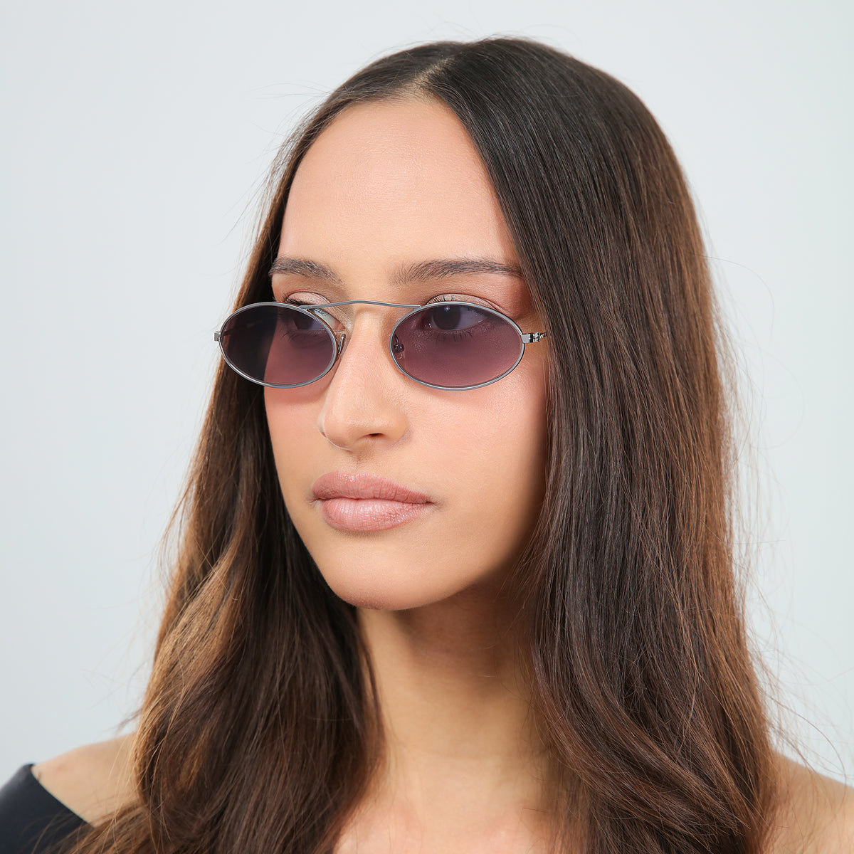 Woman wearing Sydney Sunglasses in Gunmetal with Grey Gradient lenses, side profile, Woman with brown hair in an off-the-shoulder blouse