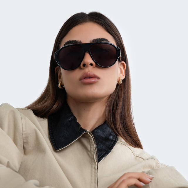 Another angle of woman in a trench coat wearing Telluride Sunglasses Black with Grey