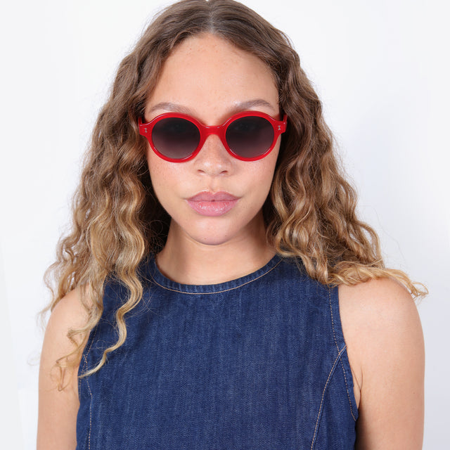 Brunette model with ombré, natural curls wearing The Met x illesteva Sunglasses Red with Grey Gradient