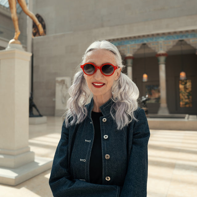 Model with silver hair at a Met Art Exhibit wearing The Met x illesteva Sunglasses Red with Grey Gradient