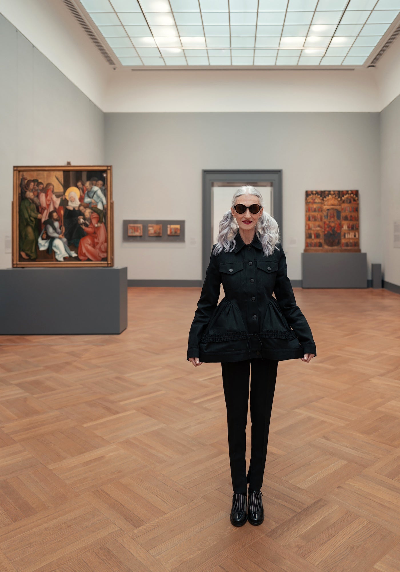 Model with silver hair wearing the Met x illesteva Sunglasses in Black in front of paintings at the Met Museum