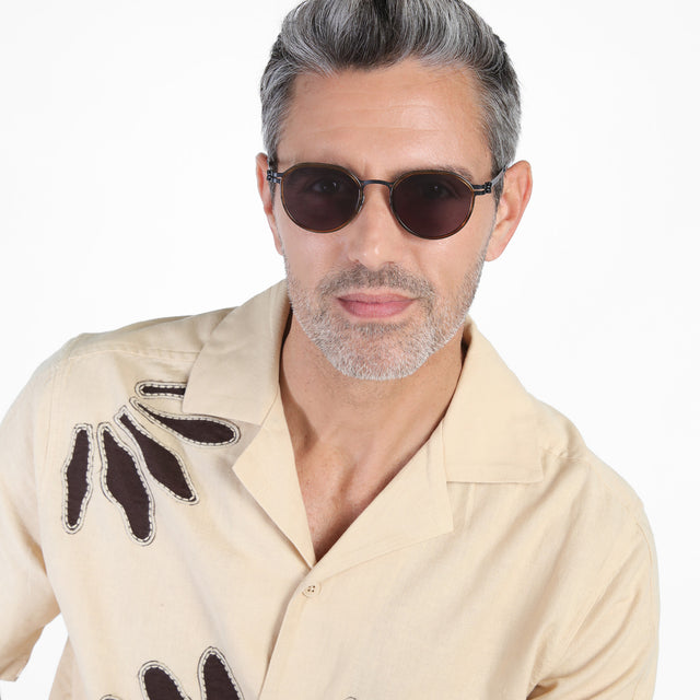 Model with salt and pepper hair and beard wearing Tompkins Titanium Sunglasses Scotch/Matte Black with Grey