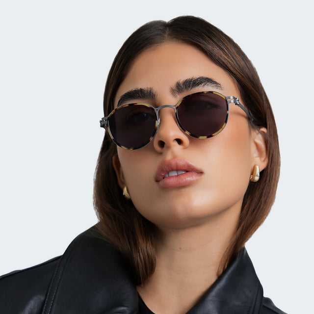 Woman in a black leather blouse wearing Tompkins Titanium Sunglasses Tortoise/Matte Silver with Grey