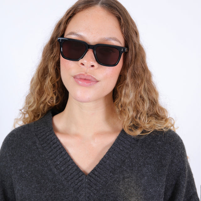 Brunette model with wavy, ombré hair wearing Toscana Sunglasses Black with Grey