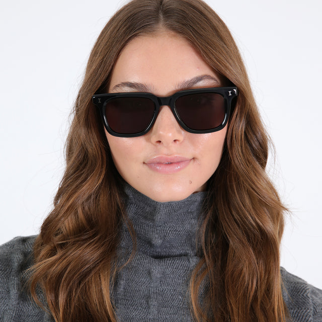 Brunette model with curled hair wearing Toscana Sunglasses Black with Grey