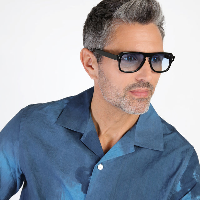 Model with salt and pepper hair and beard looking left wearing Trancoso Sunglasses Black with Blue Gradient See Through