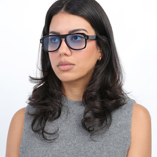 Brunette model with loose curls looking right wearing Trancoso Sunglasses Black with Blue Gradient See Through