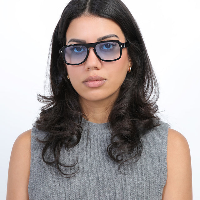 Brunette model with loose curls wearing Trancoso Sunglasses Black with Blue Gradient See Through