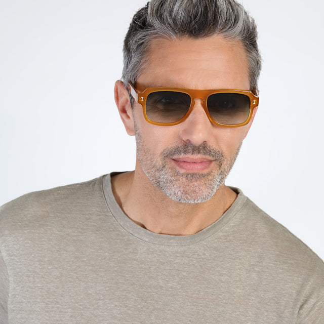 Model with salt and pepper hair and beard wearing Trancoso Sunglasses Honey with Olive Gradient