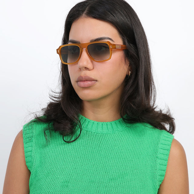 Brunette model with loose curls looking right wearing Trancoso Sunglasses Honey with Olive Gradient