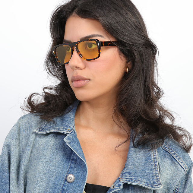 Brunette model with loose curls looking right wearing Trancoso Sunglasses Star Tortoise with Honey See Through