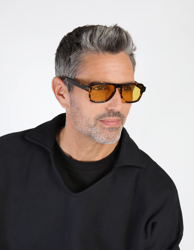 Model with salt and pepper hair and beard wearing Trancoso Sunglasses in Flame with Honey