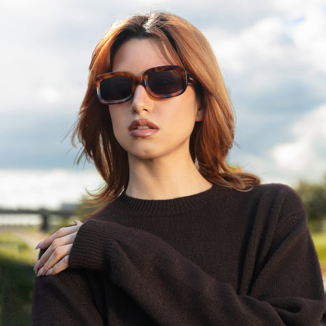 Model near a meadow wearing Vinyl Sunglasses Havana with Grey