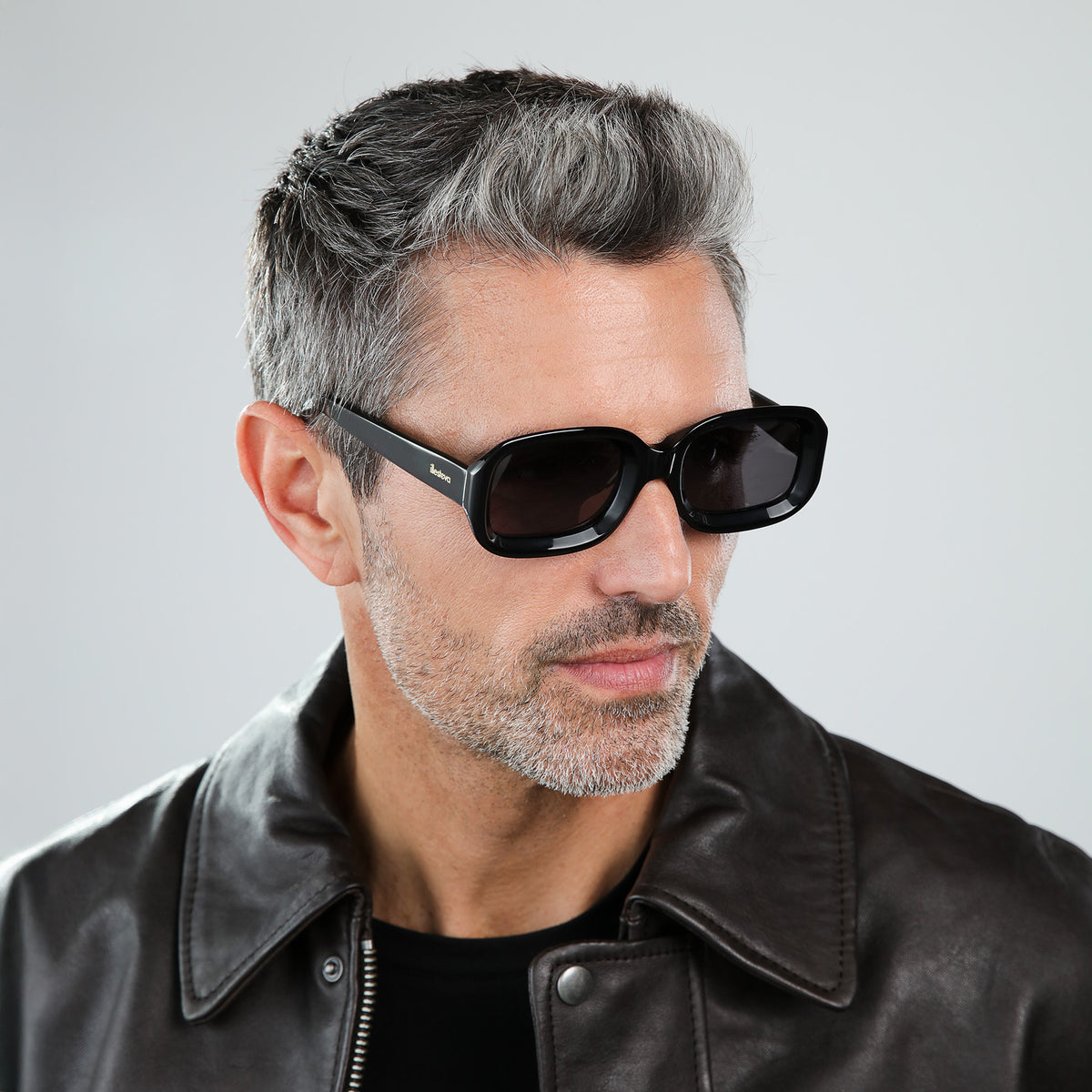 Man wearing Vinyl Sunglasses in Black with Grey lenses, side profile, Model in a leather jacket looking to his left