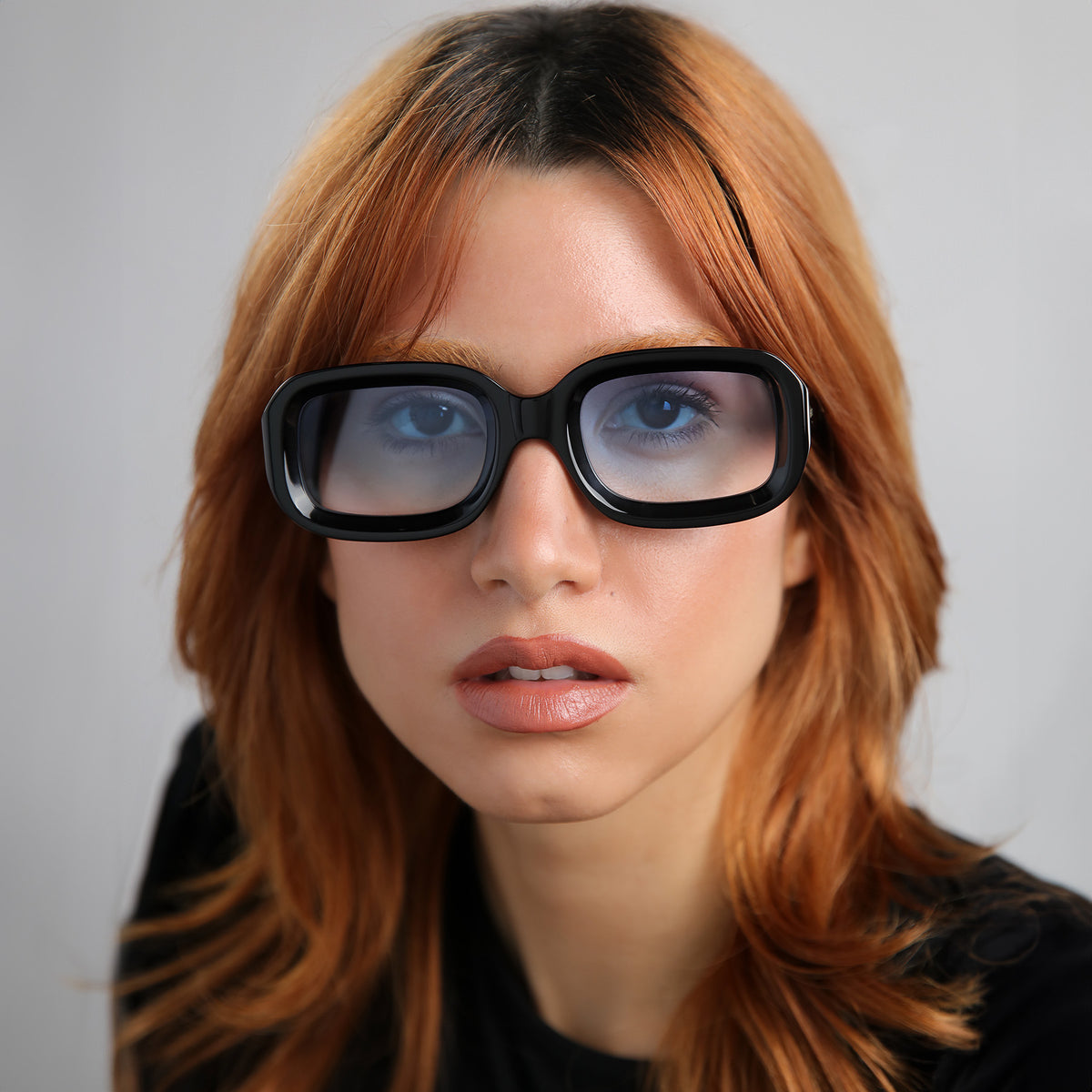 Woman wearing Vinyl Sunglasses in Black with Blue Gradient See Through lenses, Model with red hair