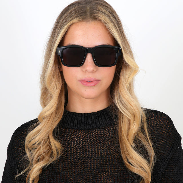 Blonde model with curled hair wearing Vito Sunglasses Black/Gold with Grey