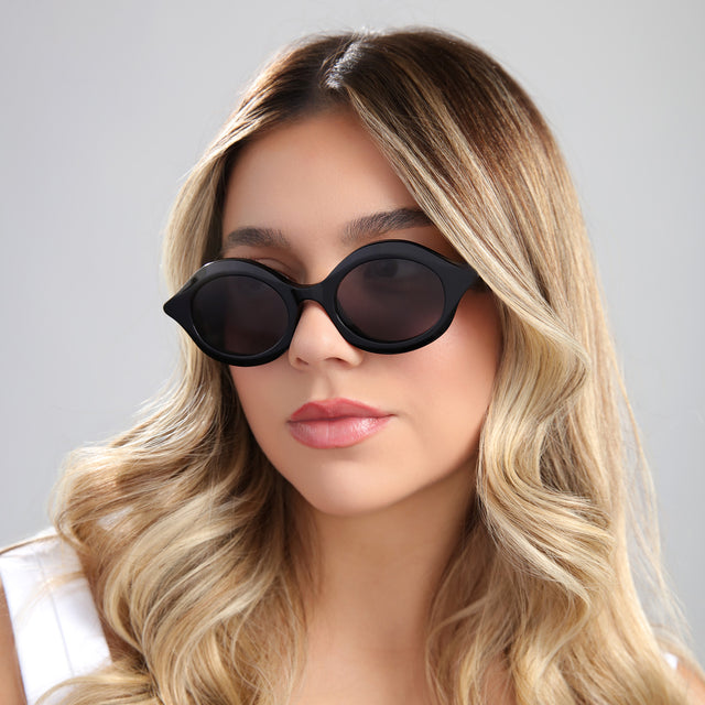 Blond woman in a white blouse wearing Willow Sunglasses Black with Grey