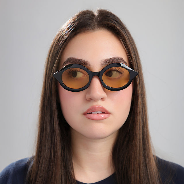 Brunette woman in a navy blouse wearing Willow Sunglasses Black with Honey See Through