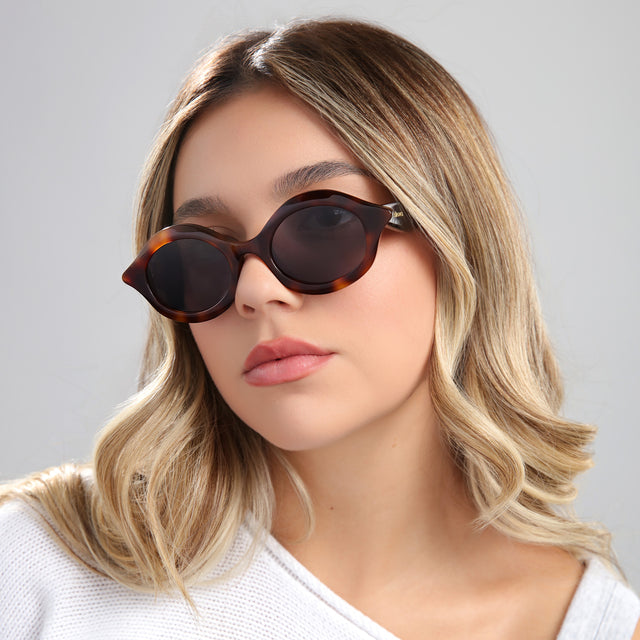 Blond woman in a white blouse wearing Willow Sunglasses Havana with Grey