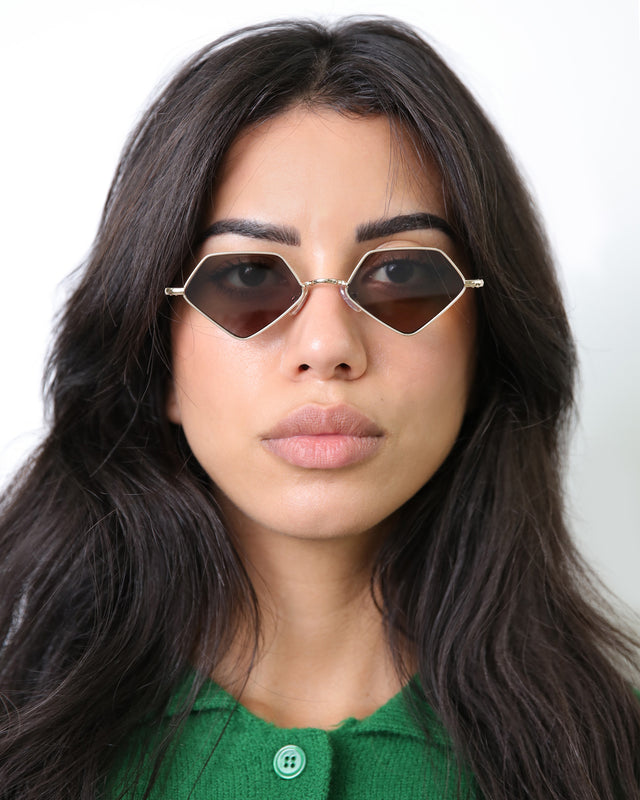Brunette model with wavy hair wearing Beak Sunglasses Gold with Grey Flat