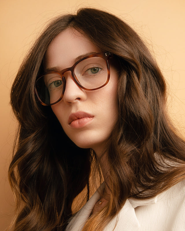 Brunette model with wavy hair wearing Essex Optical Havana Optical