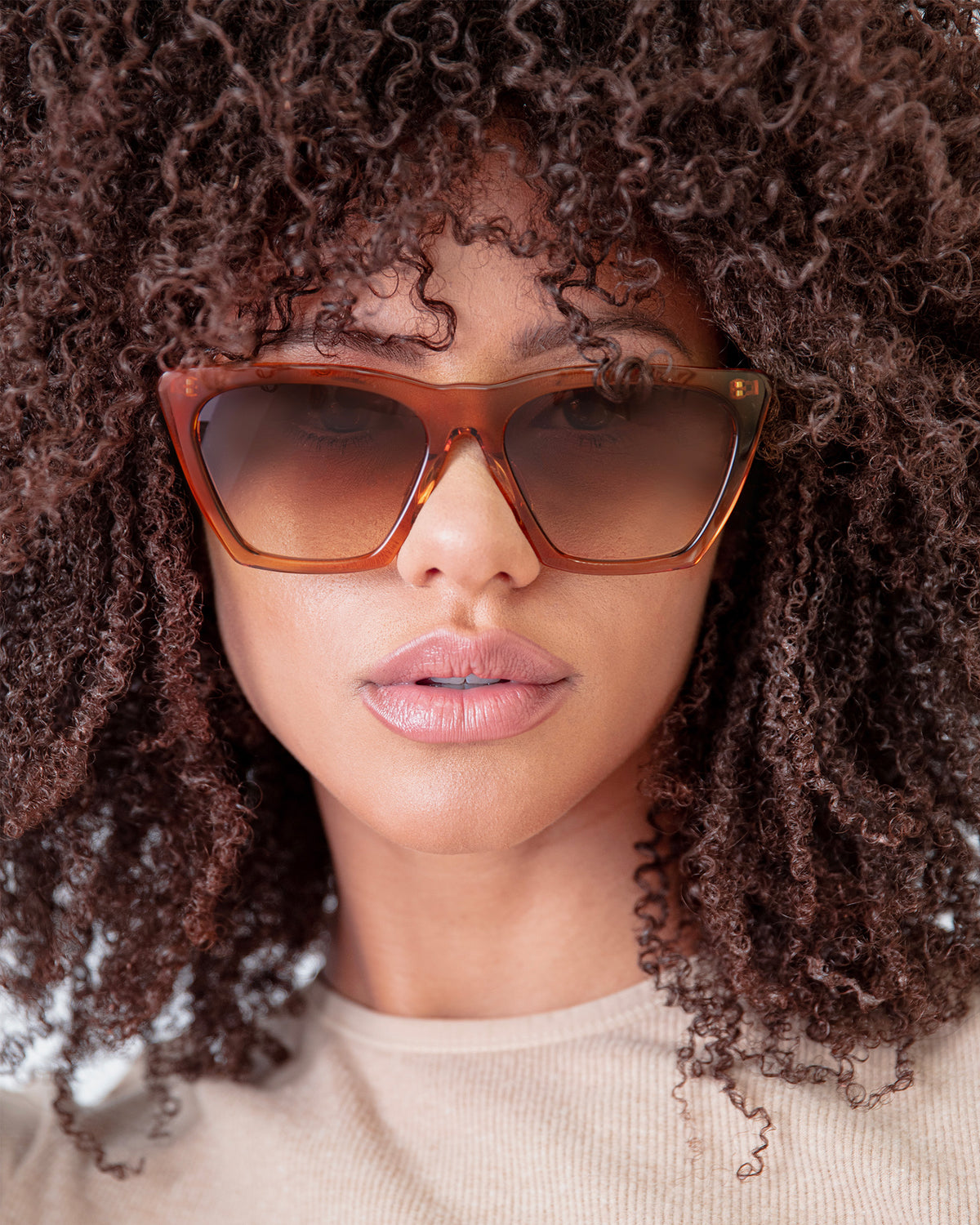 Woman wearing Lisbon Sunglasses in Cider with Brown Gradient lenses, Brunette model with afro-curly hair