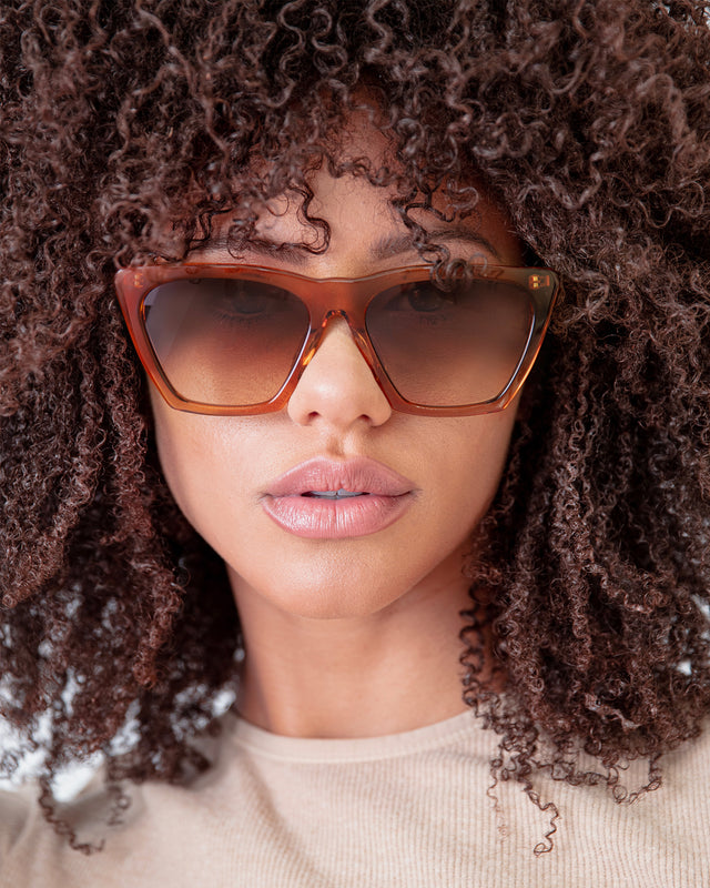 Brunette model with afro-curly hair wearing Lisbon Sunglasses Cider with Brown Gradient