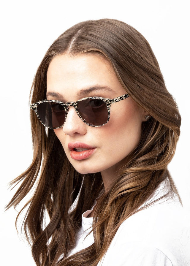 Brunette model with wavy hair wearing Whitman Sunglasses Shattered Stripes with Grey