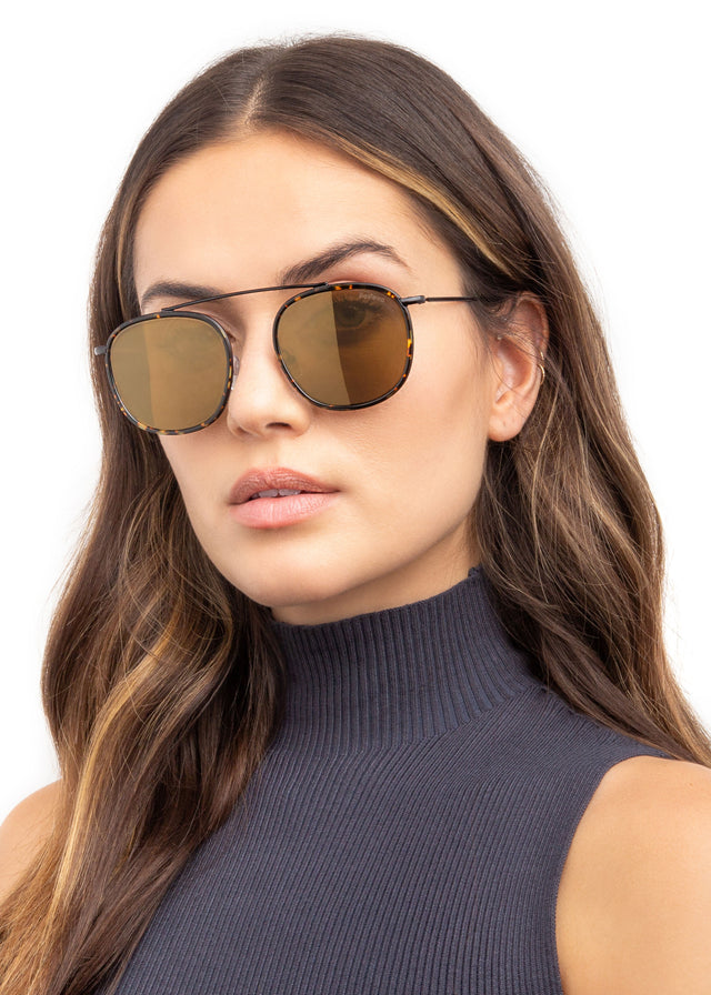 Brunette model with wavy hair wearing Mykonos Ace Sunglasses Flame/Black with Gold Flat Mirror