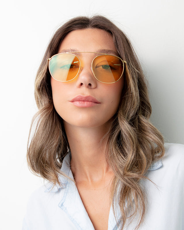 Woman with light brown hair wearing Mykonos II Sunglasses Gold with Honey Flat See Through