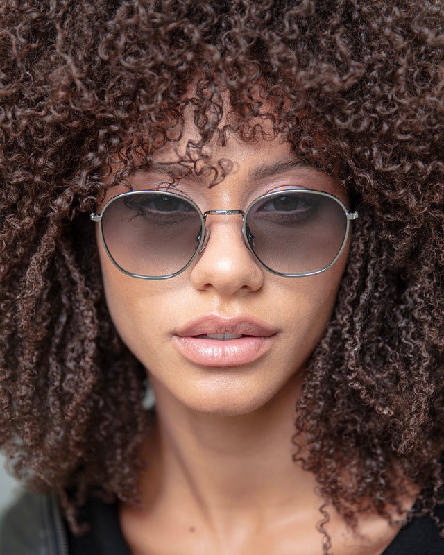 Brunette model with afro-curly hair wearing Prince 54 Sunglasses Silver with Grey Flat Gradient
