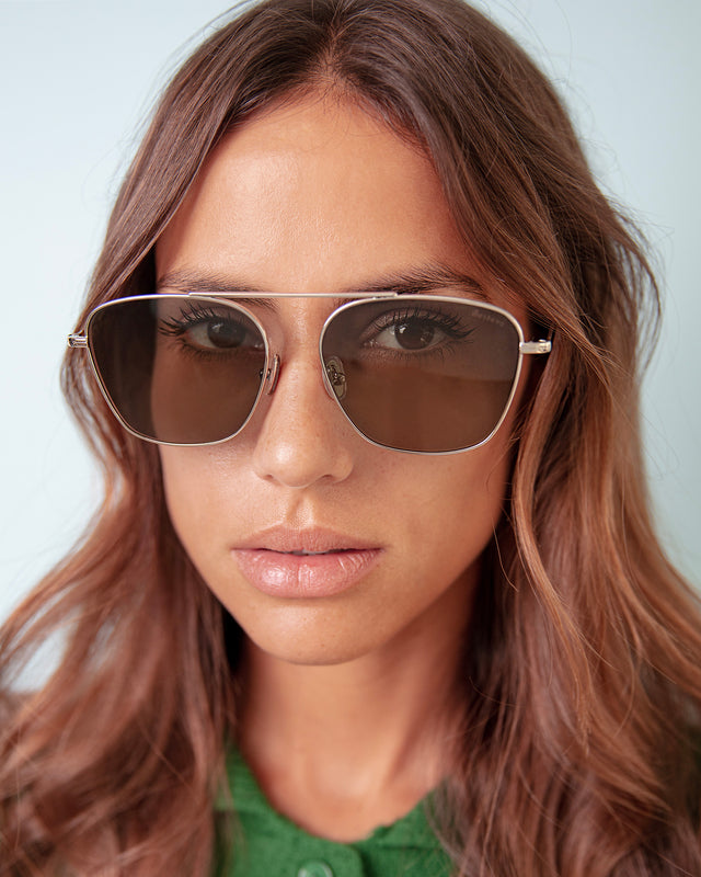Brunette model with light, wavy hair wearing Samos Sunglasses Gold with Grey Flat