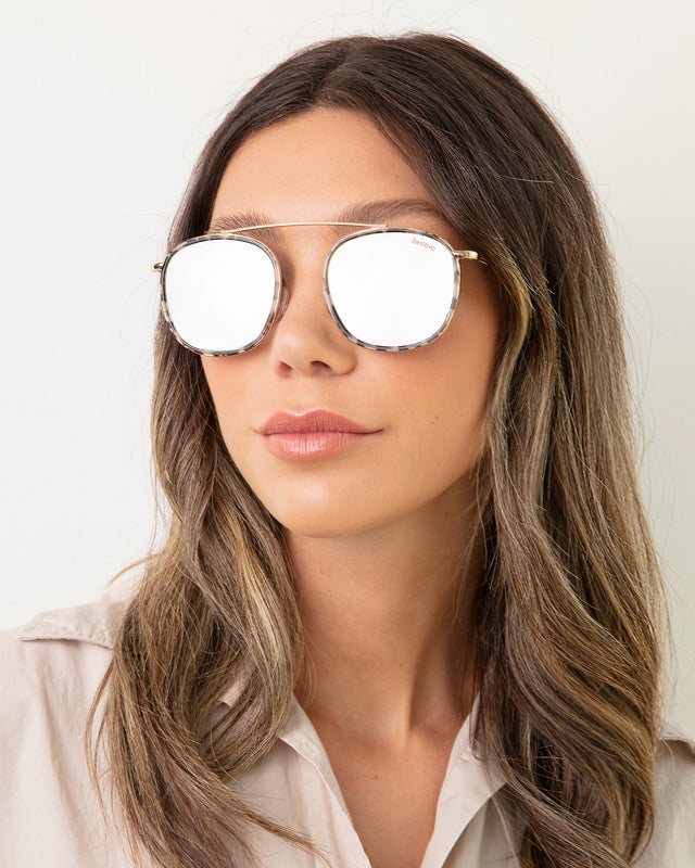 Brunette model with ombre wavy hair wearing Mykonos Ace Sunglasses White Tortoise/Gold with Silver Flat Mirror